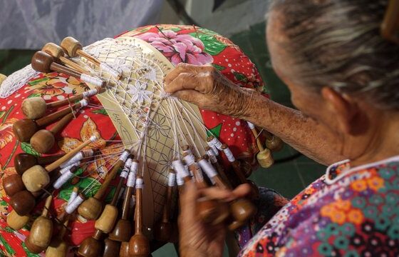 na imagem, vemos uma senhora fazendo um trabalho em renda, um dos destaques do artesanato potiguar.